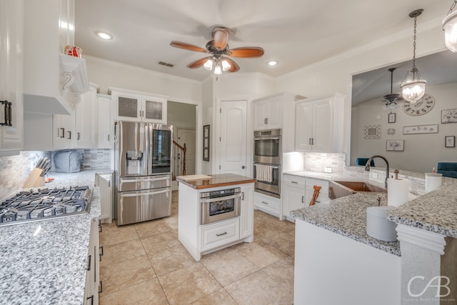 kitchen with decorative backsplash, appliances with stainless steel finishes, white cabinetry, pendant lighting, and sink