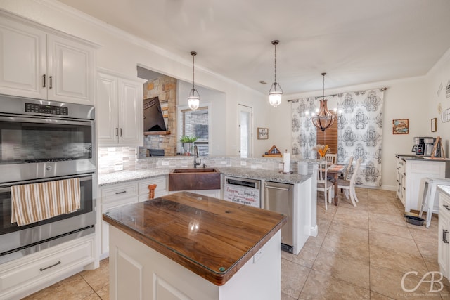 kitchen with kitchen peninsula, an inviting chandelier, sink, double oven, and a center island