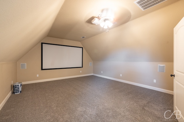 carpeted cinema room with lofted ceiling, a textured ceiling, and ceiling fan