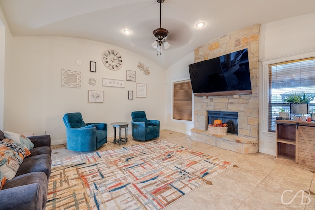 tiled living room with vaulted ceiling, a stone fireplace, and ceiling fan