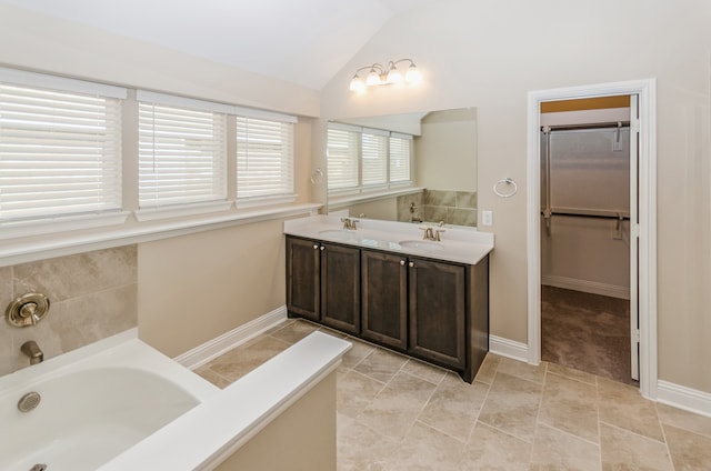 bathroom with vanity, a tub to relax in, tile patterned floors, and vaulted ceiling