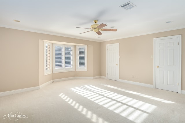 carpeted spare room with baseboards, visible vents, and crown molding