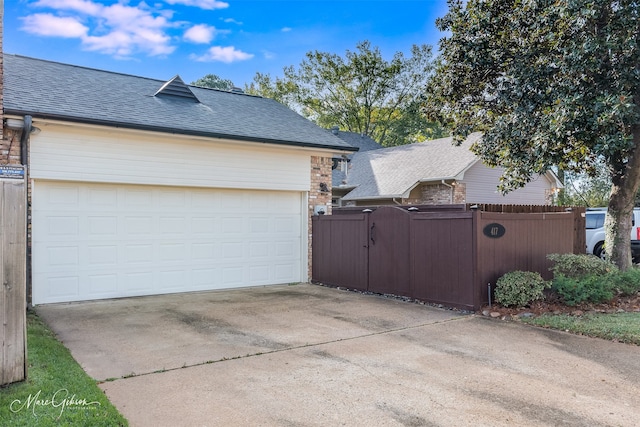 exterior space featuring a garage, roof with shingles, fence, and a gate