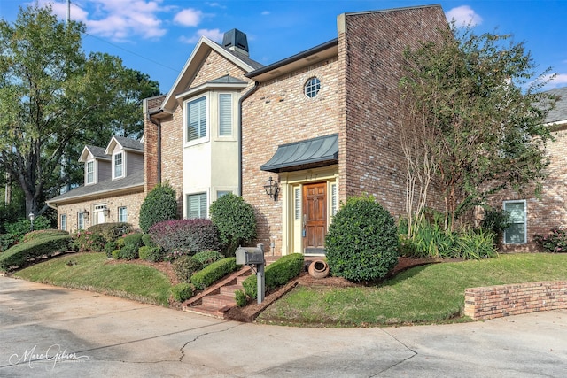 view of front of house with brick siding, a standing seam roof, and a front yard