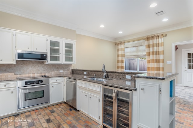 kitchen featuring appliances with stainless steel finishes, sink, dark stone countertops, white cabinets, and beverage cooler