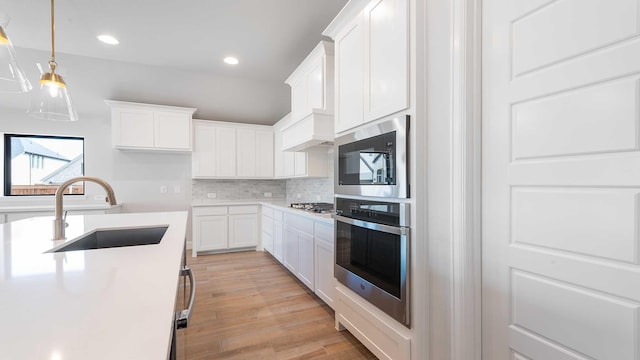 kitchen featuring light wood-type flooring, white cabinetry, appliances with stainless steel finishes, and a sink