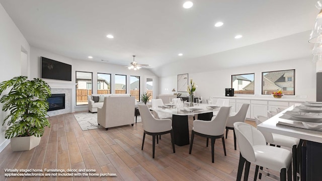 dining area featuring recessed lighting, a ceiling fan, vaulted ceiling, light wood finished floors, and a glass covered fireplace