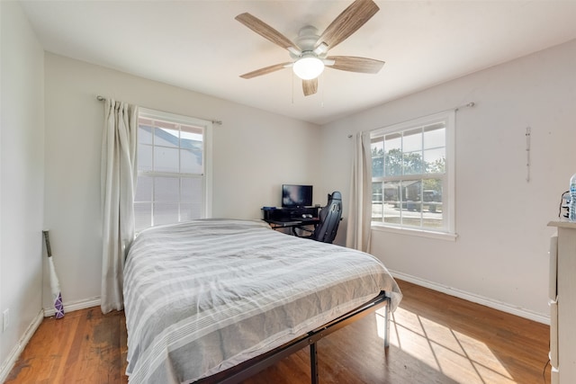 bedroom featuring hardwood / wood-style floors, multiple windows, and ceiling fan