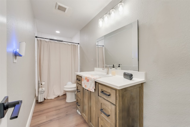 bathroom featuring vanity, hardwood / wood-style flooring, toilet, and walk in shower