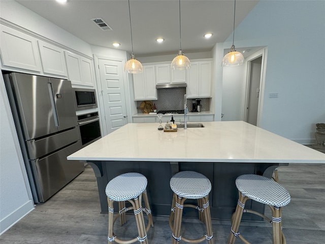 kitchen featuring a large island with sink, white cabinetry, and stainless steel appliances