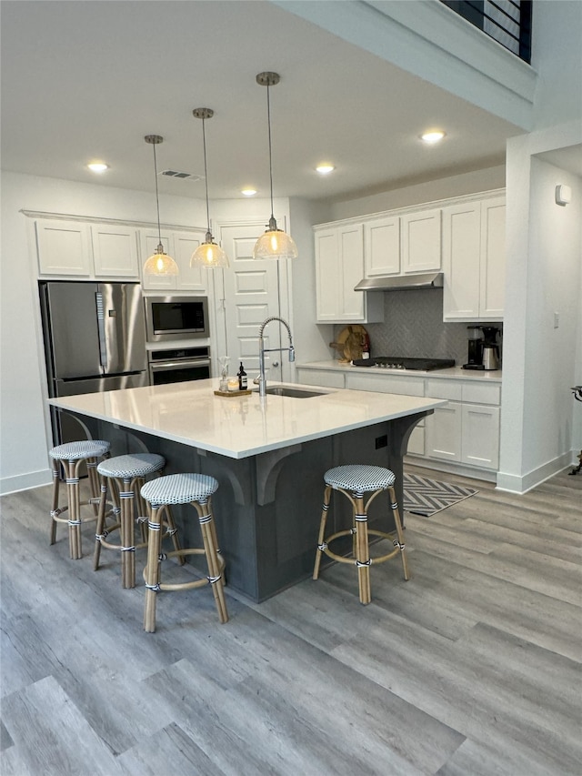 kitchen with sink, white cabinets, hanging light fixtures, and stainless steel appliances