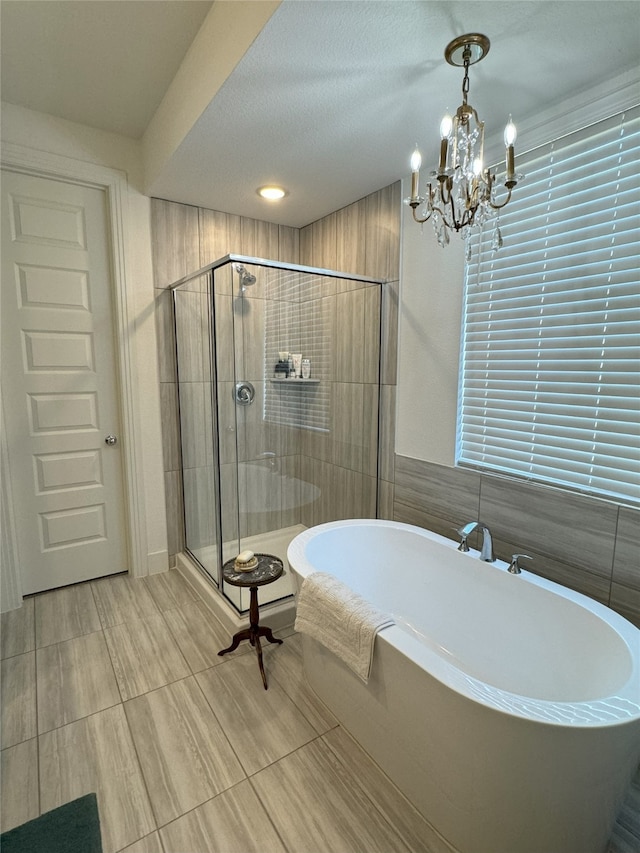 bathroom featuring separate shower and tub, a notable chandelier, and a textured ceiling