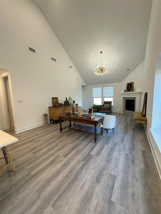 living room featuring high vaulted ceiling, wood-type flooring, and a chandelier