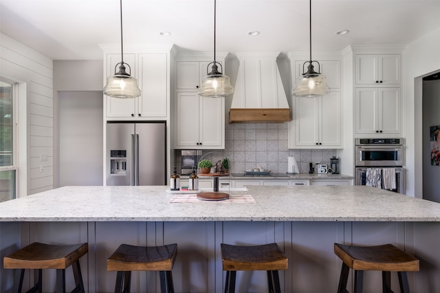 kitchen with a spacious island, custom exhaust hood, decorative light fixtures, and stainless steel appliances