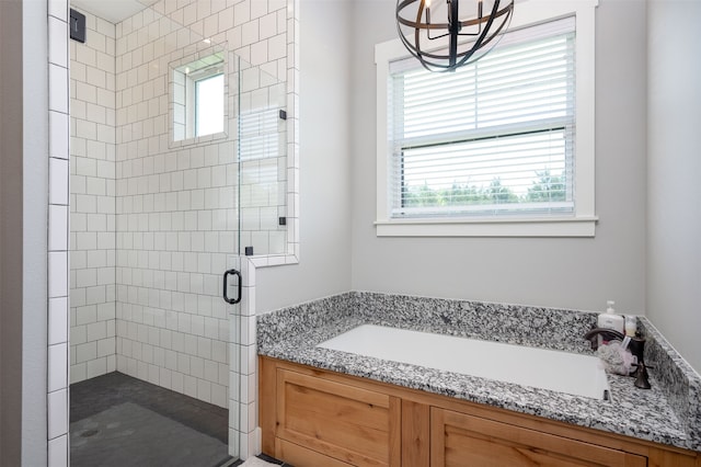 bathroom featuring a shower with door, an inviting chandelier, and a healthy amount of sunlight