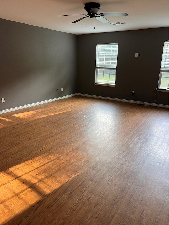 spare room featuring a healthy amount of sunlight, hardwood / wood-style flooring, and ceiling fan