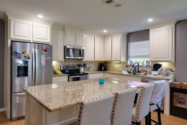 kitchen with sink, light stone countertops, stainless steel appliances, and white cabinets