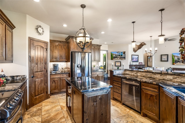 kitchen with pendant lighting, stainless steel appliances, a center island, and dark stone countertops