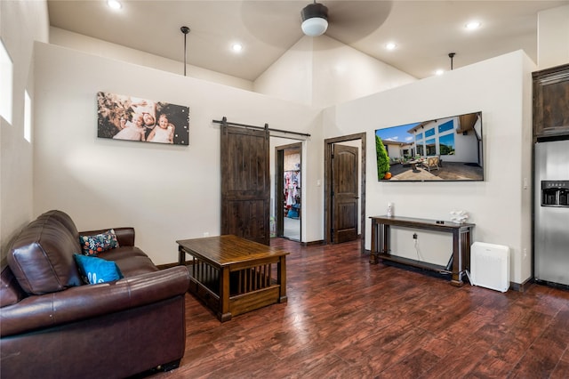 living room featuring dark wood-type flooring, ceiling fan, and a barn door