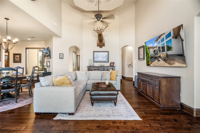 living room featuring ceiling fan with notable chandelier and dark wood-type flooring