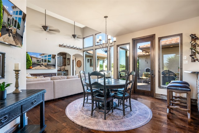 dining area featuring a towering ceiling, ceiling fan with notable chandelier, and dark hardwood / wood-style flooring