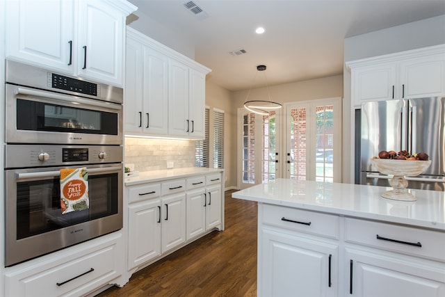 kitchen with dark wood-type flooring, appliances with stainless steel finishes, decorative light fixtures, and white cabinetry