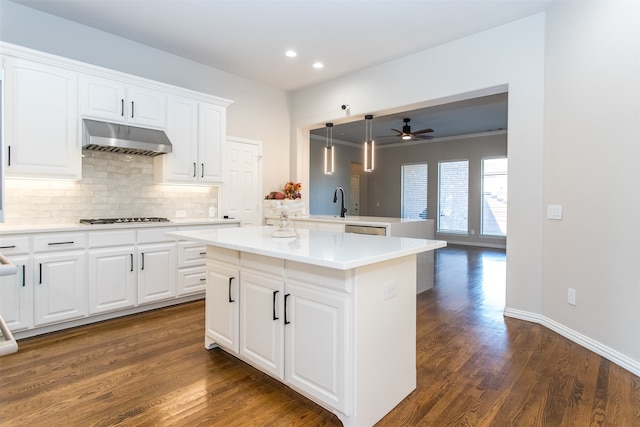 kitchen with stainless steel gas cooktop, dark wood-type flooring, hanging light fixtures, a center island, and white cabinets