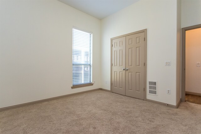 unfurnished bedroom featuring light colored carpet and a closet