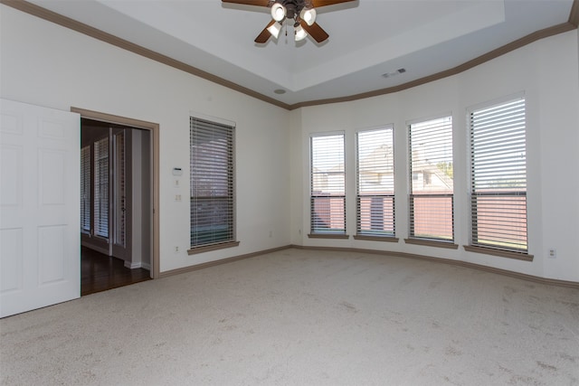 spare room with dark carpet, crown molding, a raised ceiling, and ceiling fan