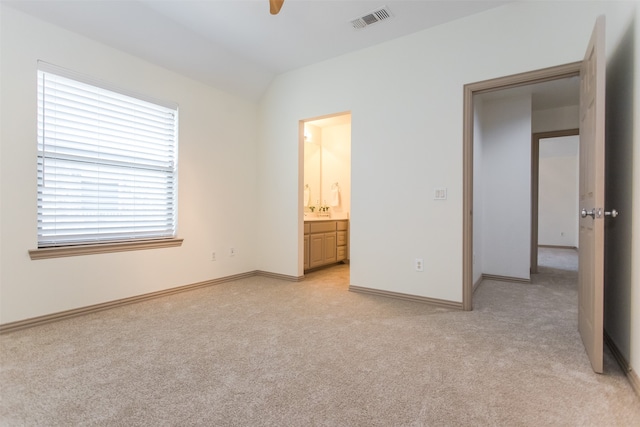 unfurnished bedroom featuring connected bathroom, vaulted ceiling, light carpet, and multiple windows