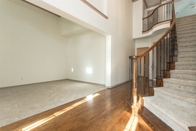 stairway with a towering ceiling and hardwood / wood-style floors