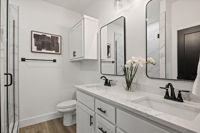 bathroom featuring a shower with door, vanity, hardwood / wood-style floors, and toilet