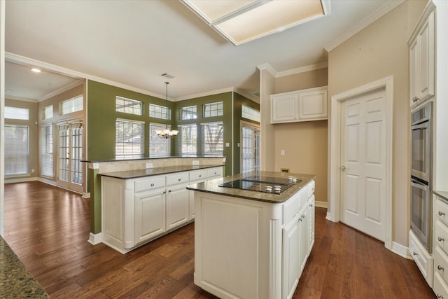 kitchen with white cabinets, a center island, hanging light fixtures, a chandelier, and black electric cooktop