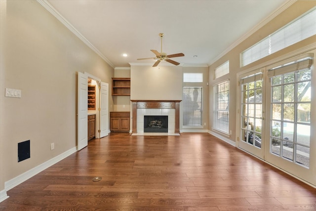 unfurnished living room with dark wood-type flooring, ceiling fan, ornamental molding, and a tiled fireplace