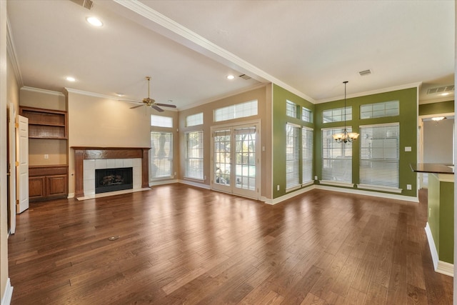 unfurnished living room featuring a tiled fireplace, dark wood-type flooring, ceiling fan with notable chandelier, and ornamental molding