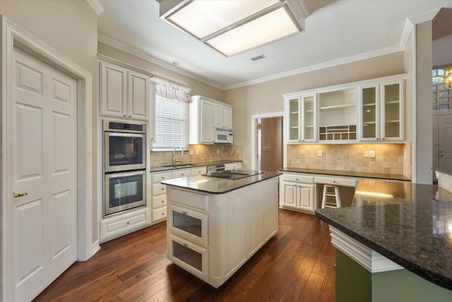 kitchen featuring white cabinetry, tasteful backsplash, a kitchen island, double oven, and sink