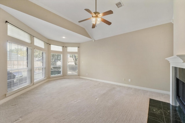 unfurnished living room featuring lofted ceiling, a wealth of natural light, ceiling fan, and a tile fireplace