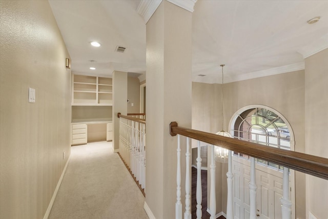 hall featuring ornamental molding, built in features, light carpet, and a chandelier