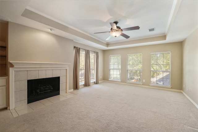 unfurnished living room featuring a wealth of natural light, a fireplace, and a tray ceiling