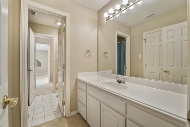 bathroom with toilet, vanity, and tile patterned floors