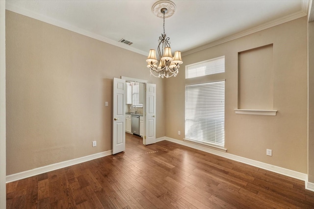 unfurnished dining area with dark wood-type flooring, sink, ornamental molding, and an inviting chandelier