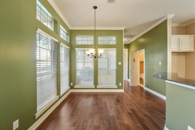 unfurnished dining area featuring dark hardwood / wood-style floors, crown molding, and a chandelier