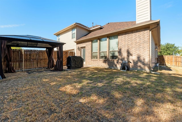 back of property with a gazebo and a lawn