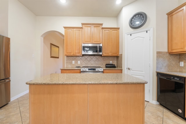 kitchen featuring decorative backsplash, a center island, light stone counters, and stainless steel appliances