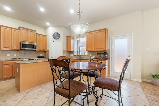 kitchen featuring tasteful backsplash, a kitchen island, appliances with stainless steel finishes, pendant lighting, and sink