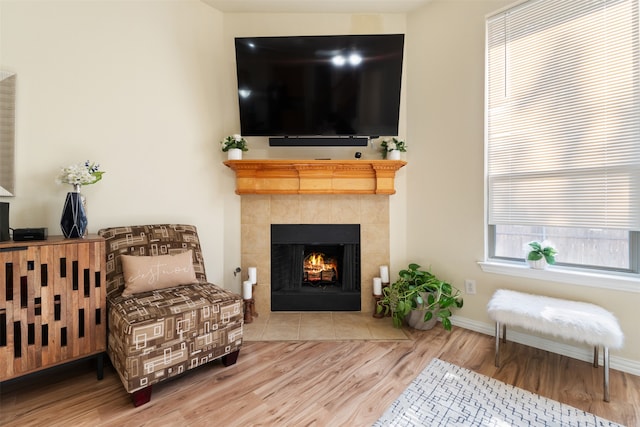 living area with wood-type flooring and a tile fireplace