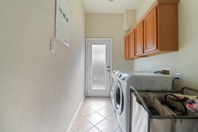 clothes washing area featuring light tile patterned flooring, cabinets, and washer and clothes dryer