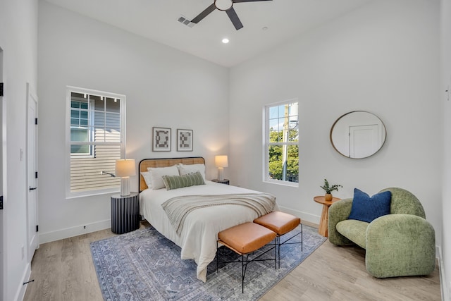 bedroom with a towering ceiling, light hardwood / wood-style floors, and ceiling fan