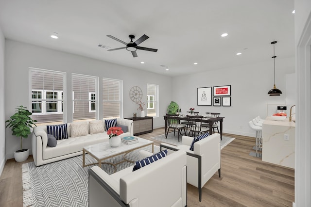 living room with ceiling fan, a wealth of natural light, and light wood-type flooring