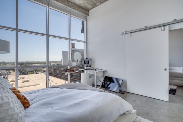 bedroom with a barn door, concrete flooring, and a towering ceiling